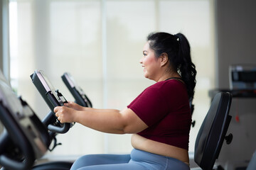 Fototapeta premium Exercise. beautiful young chubby overweight woman wearing sporty fitness clothes doing exercise indoors at gym fitness sport club, body and health care