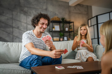 Single caucasian father play cards with his daughters at home