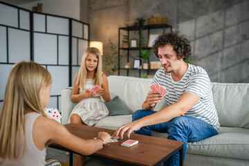 Single caucasian father play cards with his daughters at home