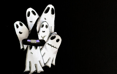 Group of little ghosts scaring, one wearing a witch's hat. Horizontal photo..