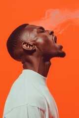 Man exhaling smoke against orange background