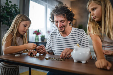 Father with daughters save coins, money in the piggy bank at home