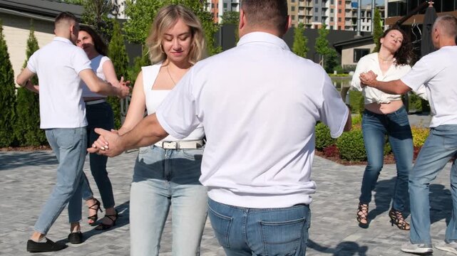 Urban mixed race couple dancing in classical public place. People dancing salsa and bachata in outdoor cafe