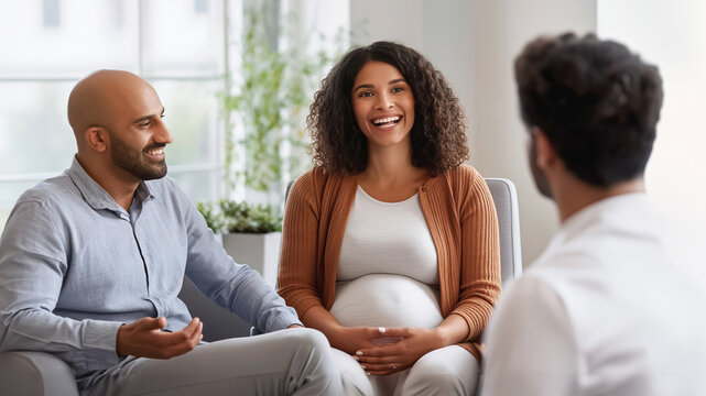 Happy pregnant couple smiling and discussing with a doctor during a medical consultation in a bright office