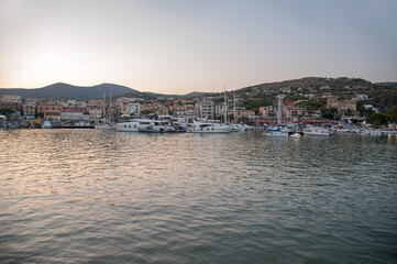 Strong afterglow of sunset behind the village with its port in the bay of Marina di Camerota, Salerno, Italy. Cilento Vallo di Diano and Alburni National Park