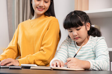 Fototapeta premium Mother and Daughter Bonding at Home. Young Girl Writing in Notebook While Mother Smiles in Background