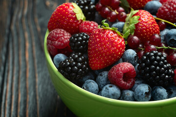 Mix of ripe colorful berries in bowl photography . Blueberry , strawberry , raspberry , blackberry and red currant . Top view