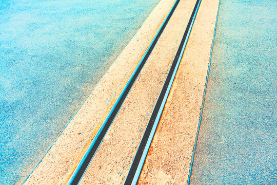 Railroad track with two parallel tracks. The tracks are made of concrete and are located on a paved road. Street tram way by in the background, showcasing urban life and transportation