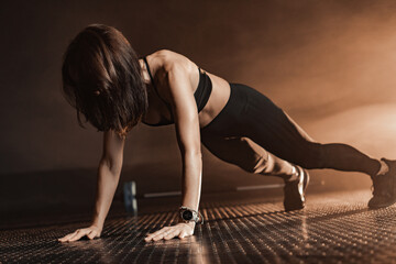A dedicated female fitness model is engaging in a powerful pushup workout in a dramatic and intense...