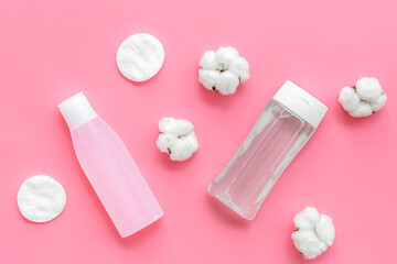 facial tonic, lotion and cotton pads for face care on pink background top view mock up