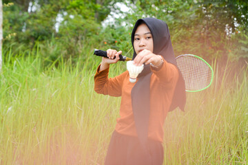 Adult Indonesian woman playing badminton in the park. Sporty urban Asian woman having fun in outdoor sports and summer activity concept games.