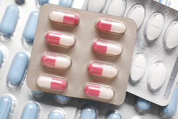 Antibiotic pills in blisters as background, top view