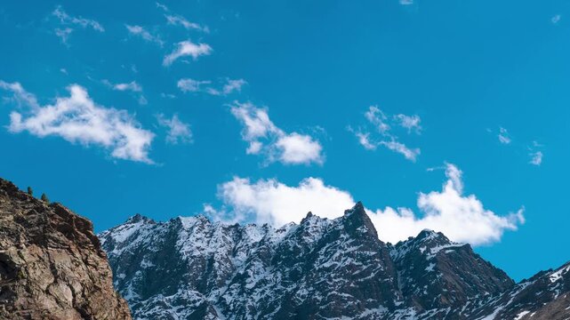 4K timelapse of snow covered Himalaya mountains and clouds moving in blue sky at Jispa, lahaul, India. Summer in mountains. Nature background. Clouds moving over mountains in sunny day.