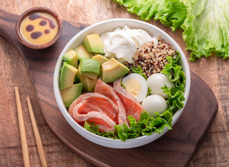 Salmon quinoa bowl with greens and vegetable on the wooden table. Balance in bowl. Top view.