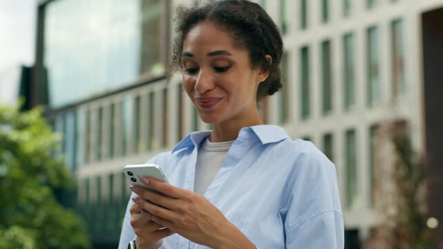 African American student girl female entrepreneur business woman lady manager businesswoman in city outside outdoors amazed wonder typing mobile phone smiling good news smartphone message win online - Powered by Adobe