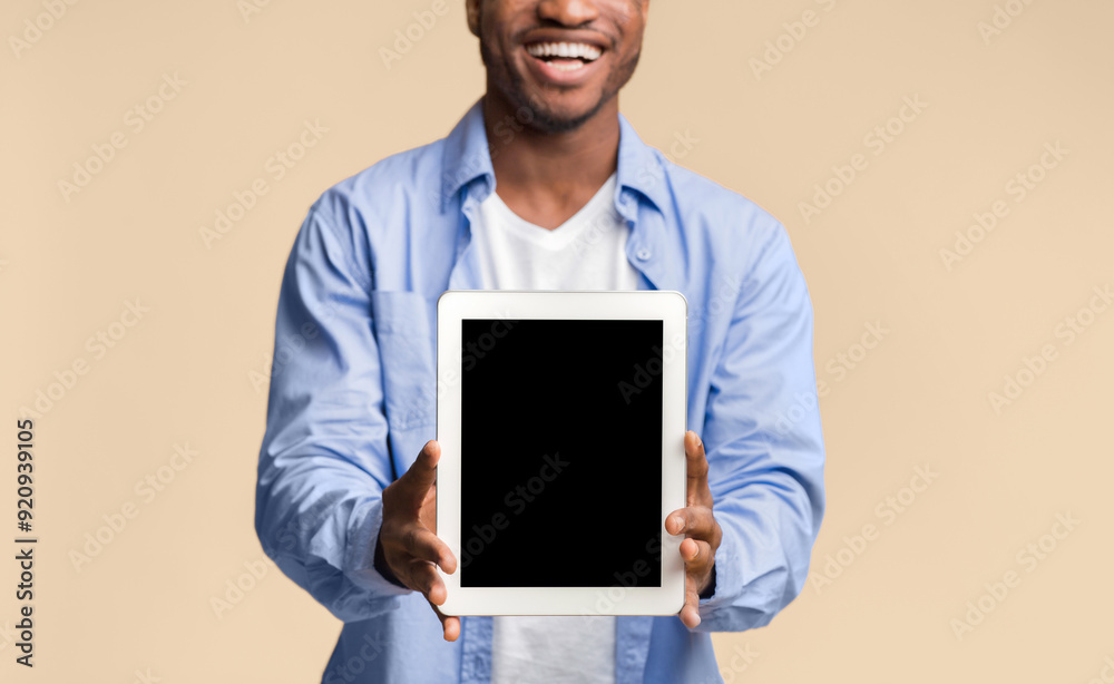 Poster great application. smiling black guy showing blank tablet computer screen posing on yellow studio ba