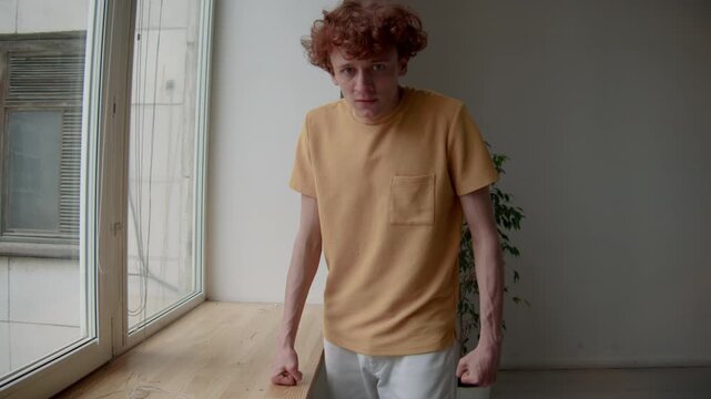Medium portrait of mad Caucasian guy in casual clothes clenching fists and looking at camera, feeling revengeful and angry indoors