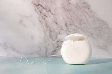 Daily dental care, dental floss container on a marble background.