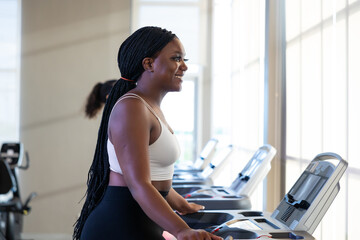 jogging on treadmill. beautiful young chubby overweight african american woman wearing sporty fitness clothes doing exercise indoors at gym fitness sport club, body and health care