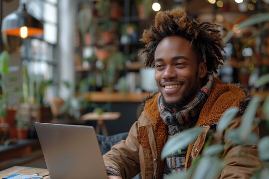 Smiling young African American man buys online with laptop, pays securely by credit card at home