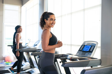 Fototapeta premium Jogging on treadmill in a gym. beautiful young hispanic woman wearing sporty fitness clothes doing exercise indoors at gym fitness sport club, body and health care