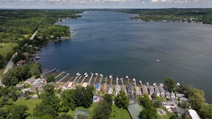 Naklejka premium Conesus Finger Lake in New York State in summer with boaters, vacation homes enjoying a day by the lake on a beautiful day with blue sky and clouds 