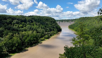 Fototapeta premium Mt Morris Dam in New York State on Genesse River at Letchworth State Park with blue sky and clouds in a beautiful countryside landscape with green trees in summer season