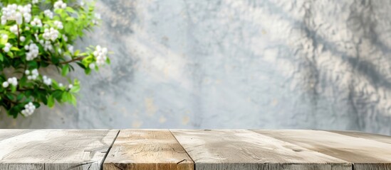 Wooden deck table with blurred background of green leaves and flowers. Nature-inspired backdrop for product display or presentation.
