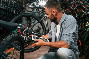 Using digital tablet. Repair man in bicycle shop, working in store