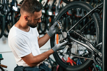 Obraz premium Spokes replacement. Repair man in bicycle shop, working in store