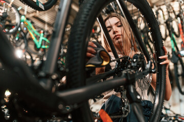 Repair woman in bicycle shop, working in store