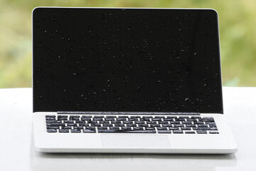 Wet laptop computer under heavy rain.