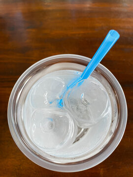 top view of ice and water in plastic glass on wood table in a restaurant