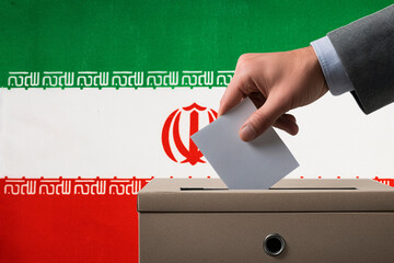 A hand holds a ballot in a ballot box against the background of the Iran flag. People cast ballots...
