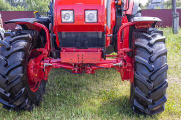 Obraz premium The front part of the tractor. A tractor for harvesting. Wheels of agricultural machinery. A tractor with big wheels.