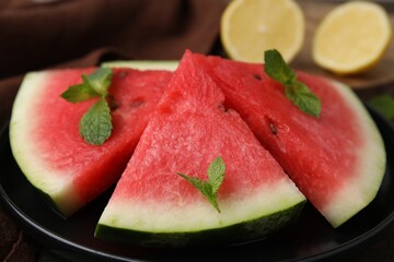 Fresh watermelon slices with mint leaves on table, closeup