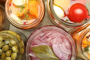 Different pickled products in jars on table, top view