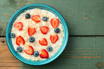 Homemade breakfast . Oatmeal with milk and berries . Top view