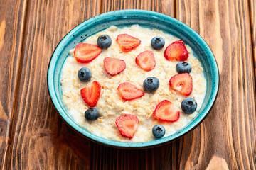 Homemade breakfast . Oatmeal with milk and berries . Top view