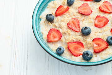 Homemade breakfast . Oatmeal with milk and berries . Top view
