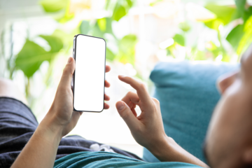 Smartphone with blank screen held by man on sofa in green living room – app or UI design mockup