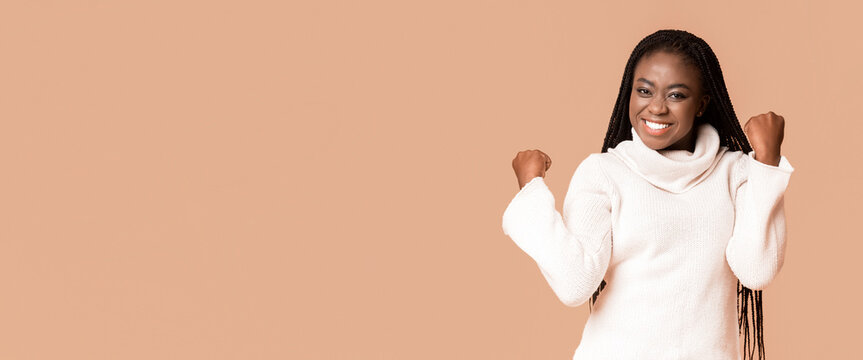 Emotional winter black woman demonstrating happiness, clenching fists, got good news, panorama