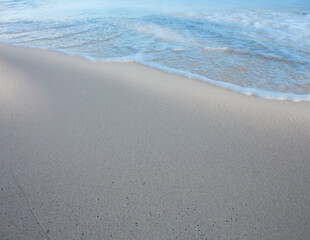 Travel background with soft wave of blue ocean on sandy beach.