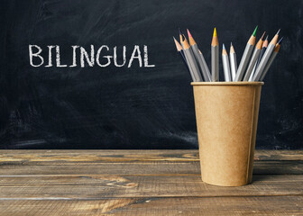 A wooden table with a brown cup and a bunch of pencils