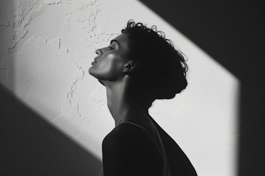 A silhouette of a woman stands against a textured wall, creating a striking contrast in light and shadow, Negative space that enhances the subject, Ai generated