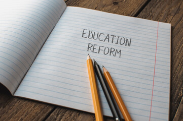 A notebook with pencils on it and the word education reform written on it