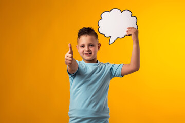 Child boy holding think cloud bubble card and showing thumb up gesture. Dreaming and idea concept