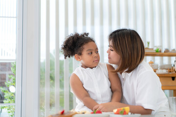 Obraz premium On a holiday, A woman and her little girl sit in a house's living room and eat fruit