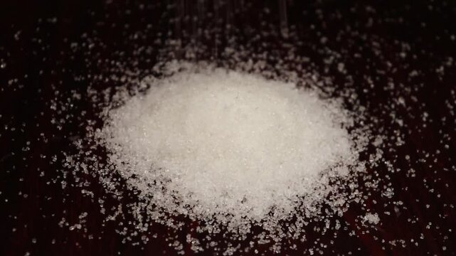 Slow motion of pile of white sugar falling on brown  background, 4k footage. 

