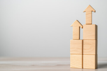 Wooden blocks arranged to symbolize growth, upward arrows highlight progress, minimalist background emphasizes focus on development and achievement in business or strategy.